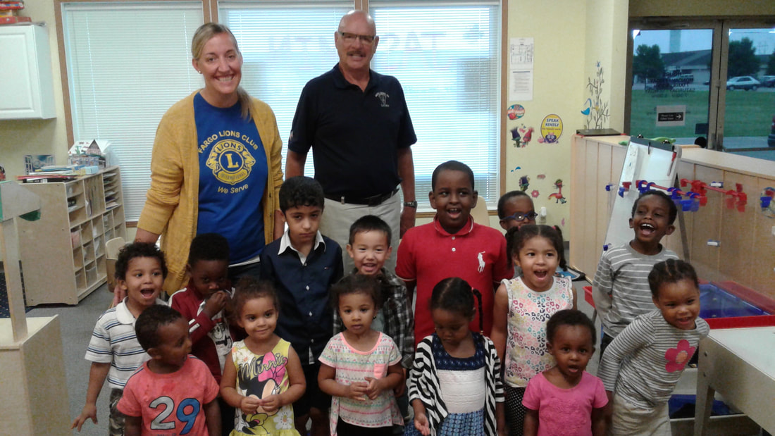 Children and visitors gathered for a group photo in a classroom